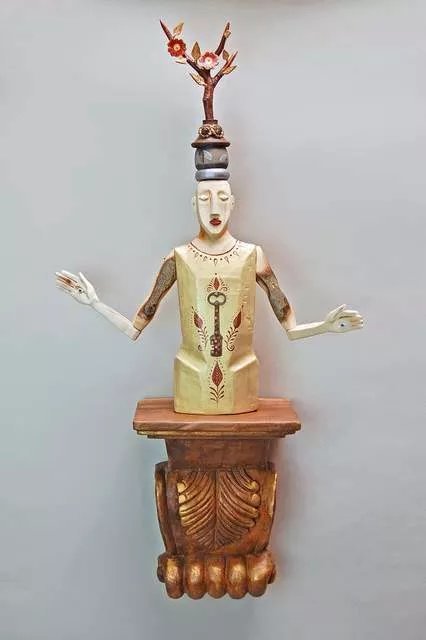 Elizabeth Frank; Illumination, 2019, Original Sculpture Mixed, 15 x 30 inches. Artwork description: 241 This figure is carved from fallen aspen branches.  It stands on a wall mounted carved wooden sconce.  Atop the head is a crown made with carved and reclaimed wood, found objects and tiny carved flowers and leaves.  There s an antique skeleton key nailed in the figure ...