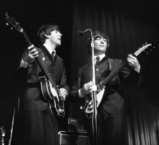 Paul Berriff: 'The Beatles Unified', 1963 Black and White Photograph, Music.  Paul McCartney and John Lennon on stage at the ABC Theater in Huddersfield Yorkshire during their first tour of the UK on 29 November 1963.  They are performing for the first time live I Want To Hold Your Hand which had been released the same day.  This is a limited...